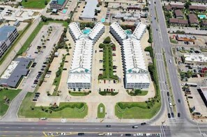 A large hotel with a central courtyard, multiple parking lots, and a main road in the background. - Casa Riviera Beachfront Condo-Great View, Two Pools (Galveston)
