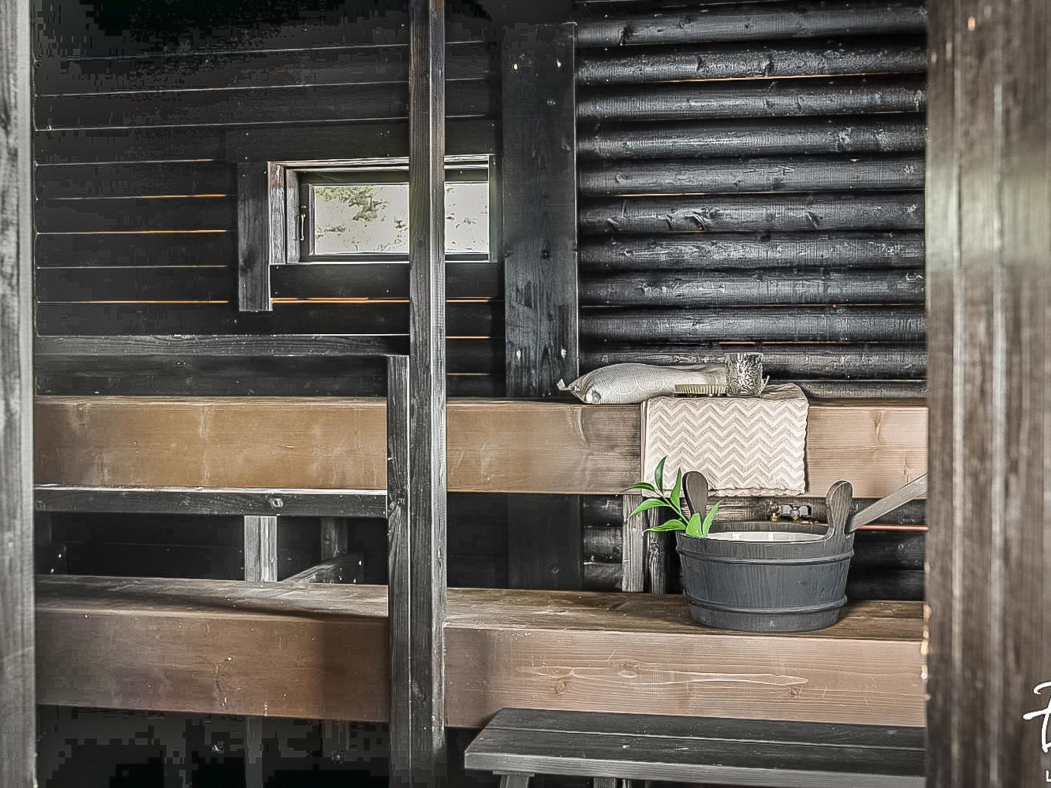 A rustic cabin interior with wooden walls, a bench, a table, and a window with a view.