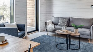 Ein modernes Wohnzimmer mit einem grauen Sofa, einem Couchtisch und einem Esstisch.