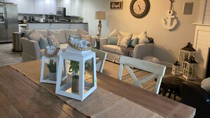 Een moderne woonkamer met een eettafel, banken en een keuken op de achtergrond.