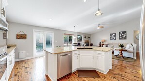 A modern kitchen with white cabinetry, a granite countertop, and a built-in dishwasher. - Hot Tub, Luxury King Bed & Yard Games ~ Quiet & Serene w Incredible Yard (Erie)