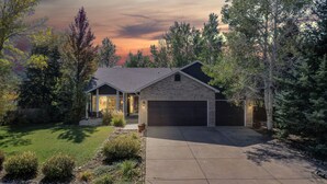 A two-story house with a garage, surrounded by trees and a well-maintained lawn. - Hot Tub, Luxury King Bed & Yard Games ~ Quiet & Serene w Incredible Yard (Erie)