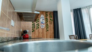 Een moderne keuken met een roestvrijstalen spoelbak, een rode waterkoker en een surfboarddecoratie aan de muur.