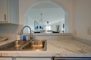 A kitchen with a double sink, white marble countertops, and a large mirror above the sink.