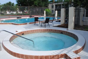 A hot tub with a tiled edge, a pool with a fence, and outdoor seating. - Chic Waterfront Condo in Cape Canaveral - 5 min from the beach! (Cape Canaveral)