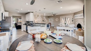 A spacious kitchen with modern appliances, a dining area with a round table set for a meal, and a fireplace in the background. - Top Choice for Guests, Golf, HPool~Spa, Bachelorettes, Quick Walk for Groceries (Scottsdale)