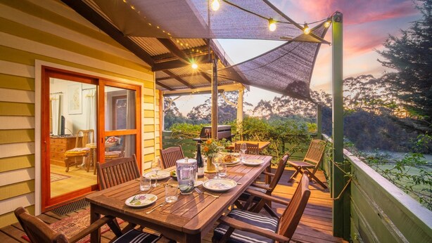 An outdoor dining area with a wooden table and chairs, a grill, and string lights. - Wooshwood: Enchanting rural getaway, pet friendly (Shadforth)
