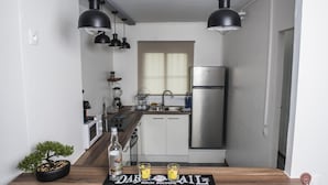 A modern kitchen with white cabinets, a stainless steel refrigerator, and black pendant lights.