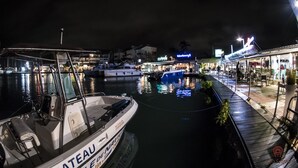 A marina with boats docked, a waterfront restaurant, and a building with illuminated signage.