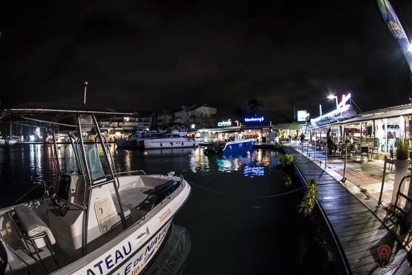 Ein Yachthafen mit vertäuten Booten, ein Restaurant am Wasser und ein Gebäude mit beleuchteter Beschilderung.
