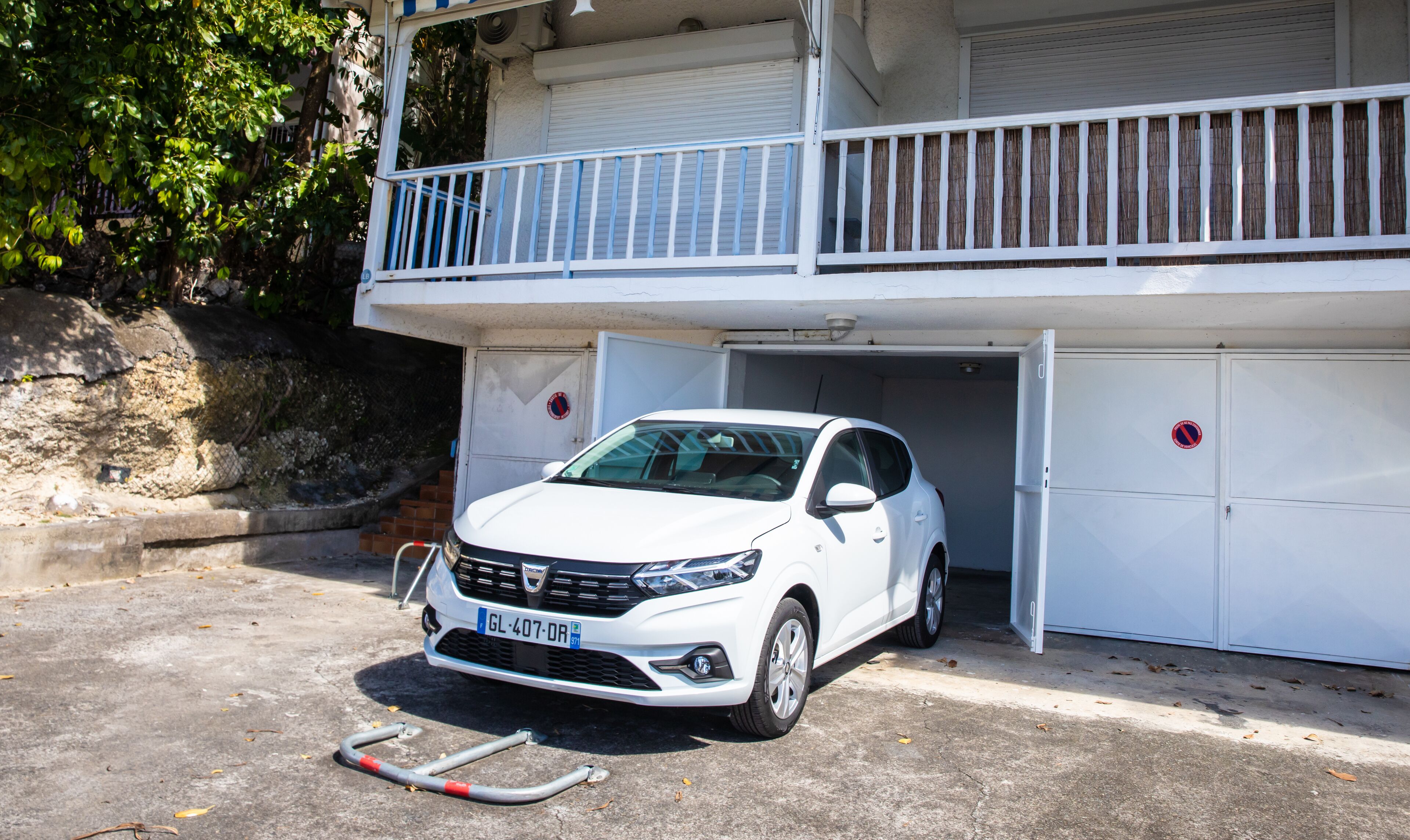 Un coche blanco estacionado en un garaje con un balcón superior.