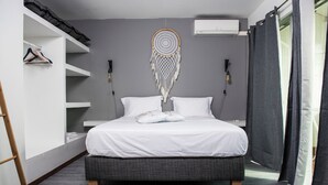 A modern bedroom with a bed, bedside tables, a wardrobe, and a dreamcatcher on the wall.