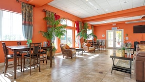 A spacious lobby with a large dining table, several chairs, a sofa, and potted plants. - Lakefront with Resort Amenities, 10 Mins from Disney (Kissimmee)
