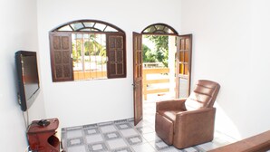 A room with a brown leather chair, a television, and a tiled floor. - HOUSE ON FRENCH BEACH (Praia do Francês)