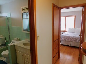 A bathroom with a toilet, sink, and mirror. There is a wooden door leading to a bedroom with a bed and window. - 1950's Retro Ranch. Conveniently located off Highway 281 (Grand Island)