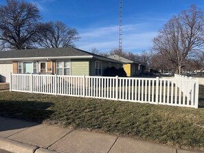 A single-story house with a white picket fence, a garage, and a clear blue sky. - 1950's Retro Ranch. Conveniently located off Highway 281 (Grand Island)
