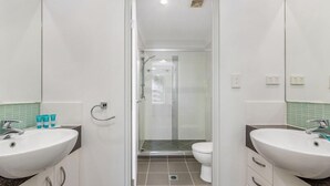 A bathroom with two sinks, a toilet, and a shower. - 3 Bedroom Poolside Villa (Sunshine Coast)
