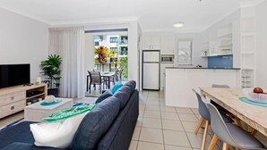 A modern apartment with a living room, dining area, and kitchen. - 3 Bedroom Poolside Villa (Sunshine Coast)