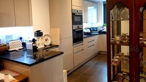 A modern kitchen with white cabinets, a black countertop, and a wooden cabinet with glass doors. - New Modern Penthouse apartment with a fantastic view (Sutton)