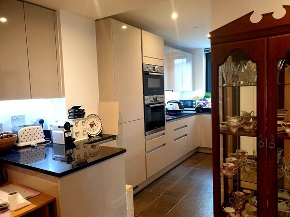 A modern kitchen with white cabinets, a black countertop, and a wooden cabinet with glass doors. - New Modern Penthouse apartment with a fantastic view (Sutton)