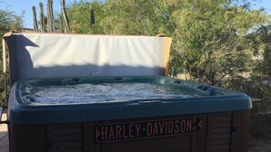 Ein Whirlpool mit der Aufschrift „HARLEY-DAVIDSON“, davor eine Bank, umgeben von Bäumen und Kakteen.