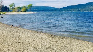 Ein Strand mit freiem Blick auf das Wasser und sanfte Hügel in der Ferne.