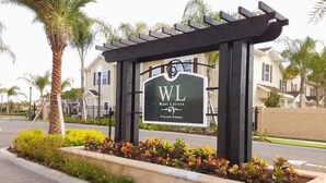 A sign for West Lucaya Village Resort with a pergola structure and landscaped garden. - Lovely Townhouse in a resort located less than 10 minutes from Disney complex. (Kissimmee)