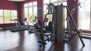 A gym with treadmills, weight machines, and a wall-mounted exercise bike. - Lovely Townhouse in a resort located less than 10 minutes from Disney complex. (Kissimmee)