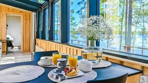 A breakfast table with a vase of flowers, orange juice, and pastries.