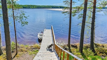 En träbrygga som leder ut till en lugn sjö, omgiven av träd.