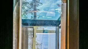 A wooden cabin with a glass door leading to a dock over water.