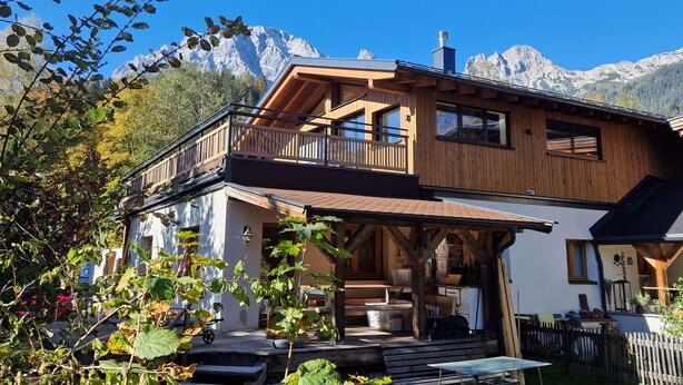 A wooden chalet with a balcony, a covered porch, and a view of mountains. - Comfortable vacation home near ski slopes, large sunny garden  (Leogang)