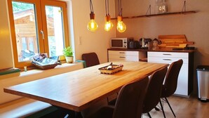 A modern kitchen with a wooden table, chairs, and a built-in oven. - Comfortable vacation home near ski slopes, large sunny garden  (Leogang)