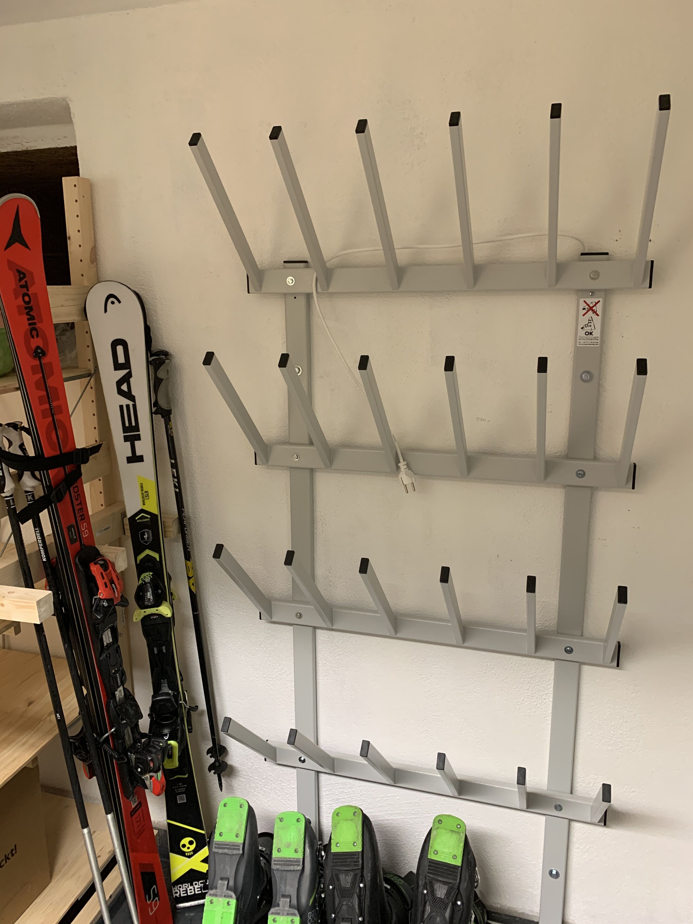 Un soporte de pared para esquíes con varios ganchos para esquíes y tablas de snowboard.