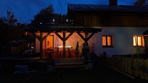 A wooden house with a covered porch and a small table. - Comfortable vacation home near ski slopes, large sunny garden  (Leogang)