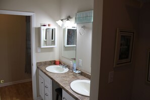 A bathroom with two sinks, a mirror, a towel rack, and a 'CALM' sign.