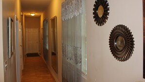 A hallway with wooden flooring, a door at the end, and decorative mirrors on the walls.