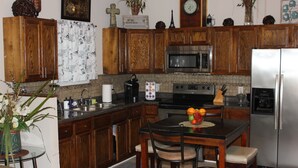 A kitchen with wooden cabinets, a stainless steel refrigerator, a microwave, and a dining table with chairs.