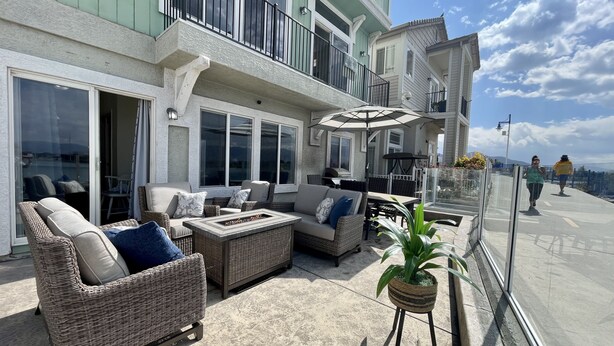 Une terrasse dotée de meubles en osier, d’un foyer extérieur et d’une plante en pot.