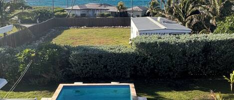 A swimming pool with a view of the ocean and palm trees.