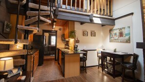 A spacious kitchen with a wooden island, a dining area with a table and chairs, and a staircase leading to an upper level.