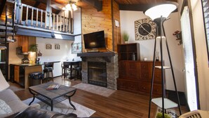 A spacious living area with a fireplace, a television, and a dining area.