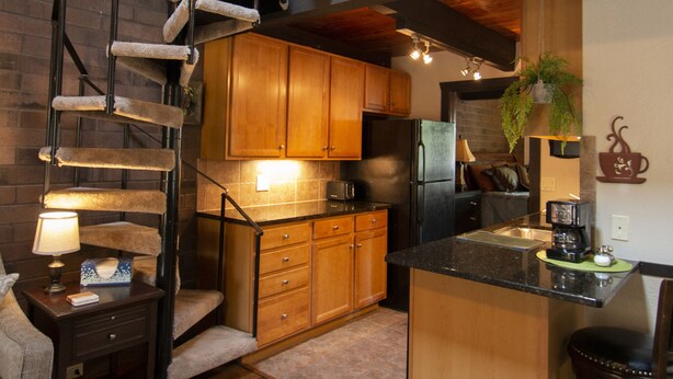 A modern kitchen with wooden cabinets, a built-in island, and a spiral staircase.
