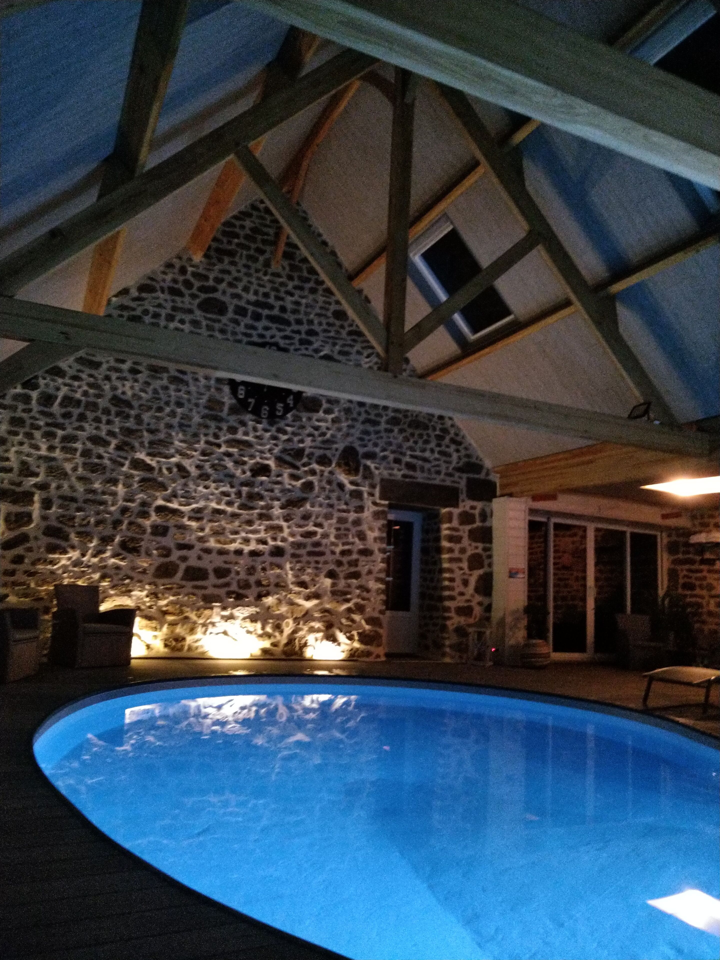 Ein Steinhaus mit Pool, Holzbalken und einer Steinmauer.