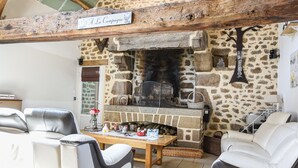 Un interior rústico con chimenea de piedra, vigas de madera y un techo alto.