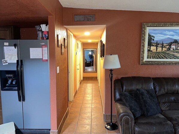 Een gang met een koelkast, een bank en een lamp.