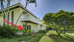 Ein zweistöckiges Haus mit Balkon, umgeben von üppiger Vegetation und einem gepflegten Rasen.