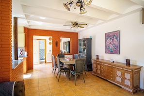 A dining area with a brick wall, a ceiling fan, and a dining table with chairs.