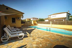 A poolside area with lounge chairs and a stone-tiled deck.