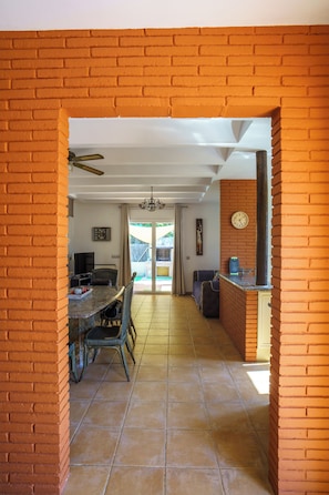 A spacious room with a dining area, kitchen, and a view through a doorway.